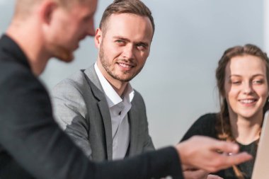Kapat. Genç meslektaşlar iş toplantısında dizüstü bilgisayar kullanıyorlar..