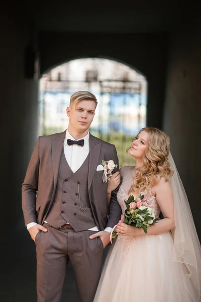 Sposa e sposo in piedi sotto l'arco dell'edificio della città. — Foto Stock