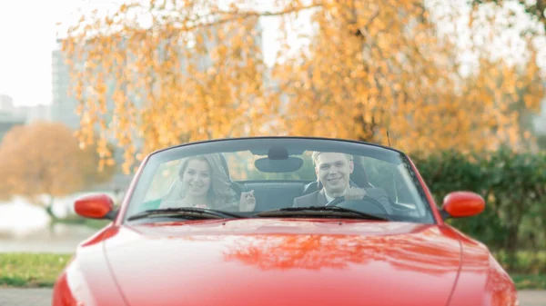 Šťastná nevěsta a ženich sedí v luxusním autě. — Stock fotografie
