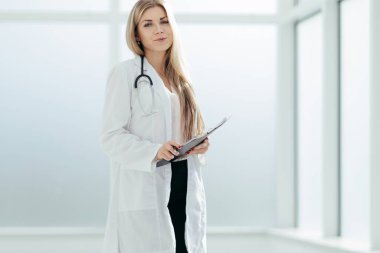 Elinde dosya olan bir kadın terapist, hastanenin yanında duruyor.