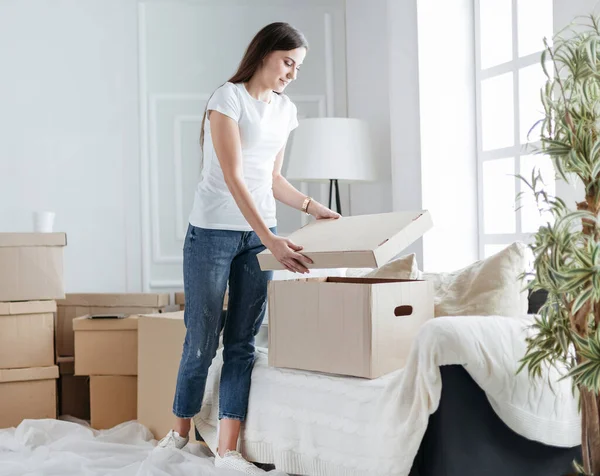 Mujer joven abriendo una caja en un nuevo apartamento — Foto de Stock