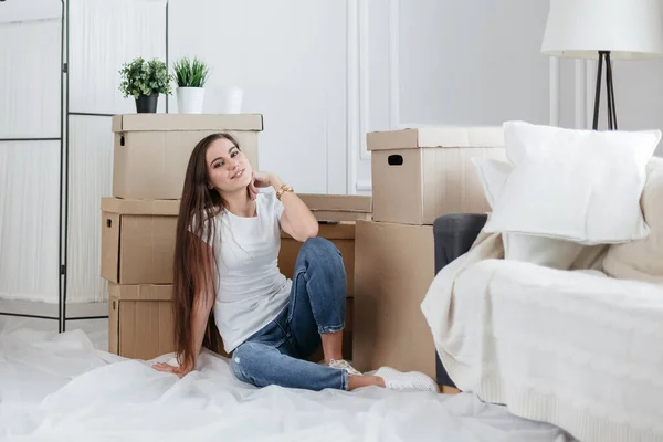 Šťastná mladá žena sedí na podlaze ve svém novém bytě — Stock fotografie