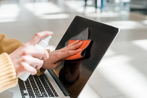 Kapat. Genç bir kadın laptopunu temizlemek için antiseptik kullanıyor. — Stok fotoğraf