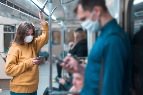 Jovem mulher em uma máscara protetora de pé em um carro de metrô. — Fotografia de Stock