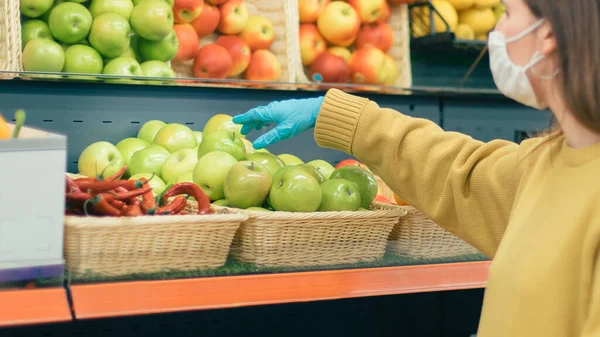 Femme décontractée en masque de protection et gants acheter des fruits. — Photo