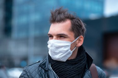 Koruyucu maskeli adam kendinden emin bir şekilde ileriye bakıyor.