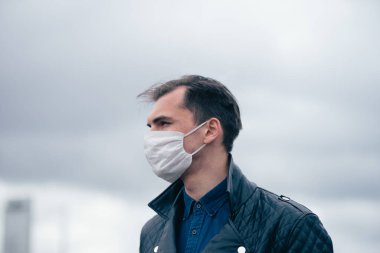 Kapat. Koruyucu maskeli bir gencin portresi.