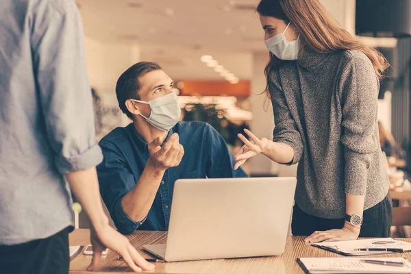 employees in protective masks discussing work issues.