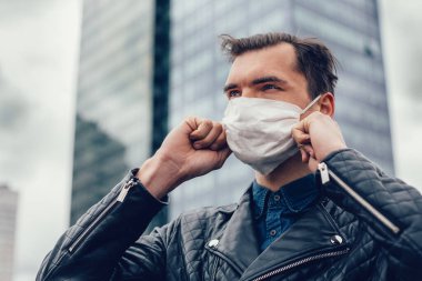 Şehir caddesinde duran koruyucu maskeli bir adam.