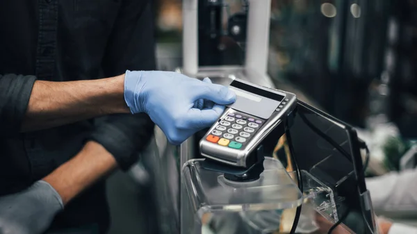 Klient w rękawiczkach ochronnych płacący za towary w supermarkecie — Zdjęcie stockowe