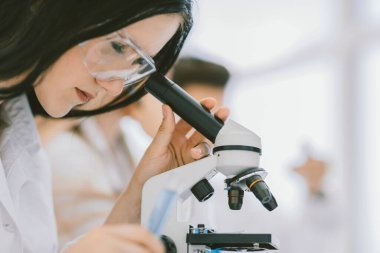 Yakın çekim. Bilim adamı mikroskoba bakar.