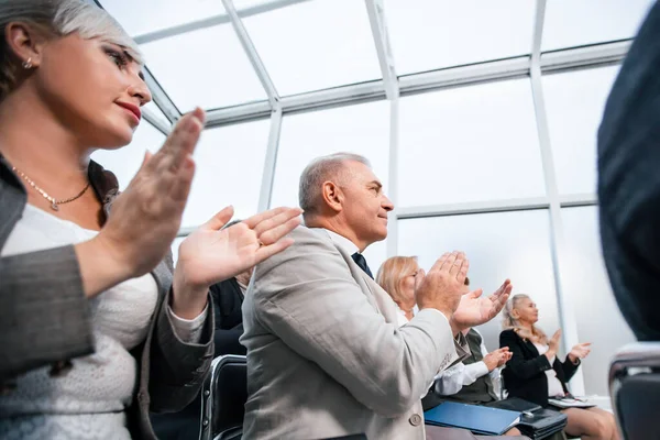 Vista laterale. sorridenti ascoltatori di seminari aziendali applaudono insieme . — Foto Stock