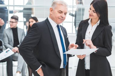 İş adamı ve işkadını bir iş belgesini tartışıyor.