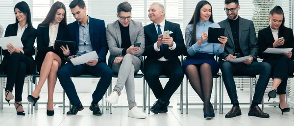 Grupo de empresários usam seus gadgets antes de iniciar uma reunião de negócios — Fotografia de Stock