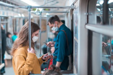çeşitli yolcular metro vagonuna biniyor.