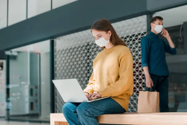 Junge Frau arbeitet an einem Laptop, während sie vor einem städtischen Gebäude sitzt — Stockfoto