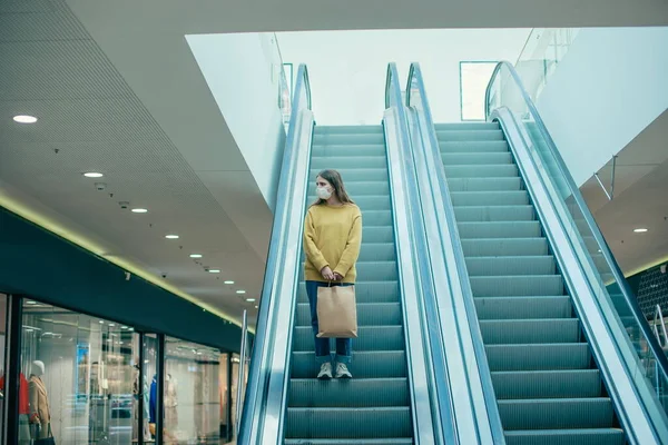 Einsame Frau mit Schutzmaske steht auf der Rolltreppe — Stockfoto