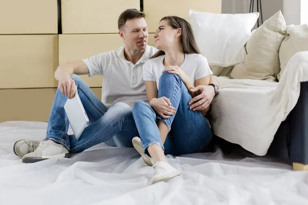 Glückliches Paar sitzt in einer neuen Wohnung neben Kisten — Stockfoto