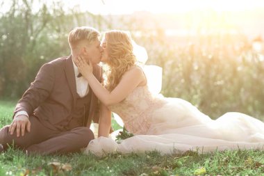 Gelin ve damat şehir parkında çimlerde oturuyor..