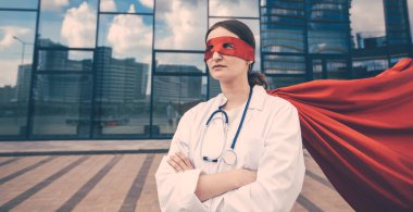 Şehir caddesinde duran, süper kahraman yağmurluklu kadın sağlık görevlisi..