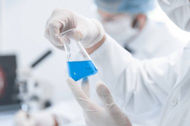 Kapat. Tıp şişesindeki sıvıya bakan bir bilim adamı..