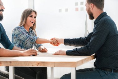 Gülümseyen iş kadını iş ortağıyla tokalaşıyor.