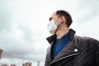 Modern bir şehrin arka planında koruyucu maskeli bir adam