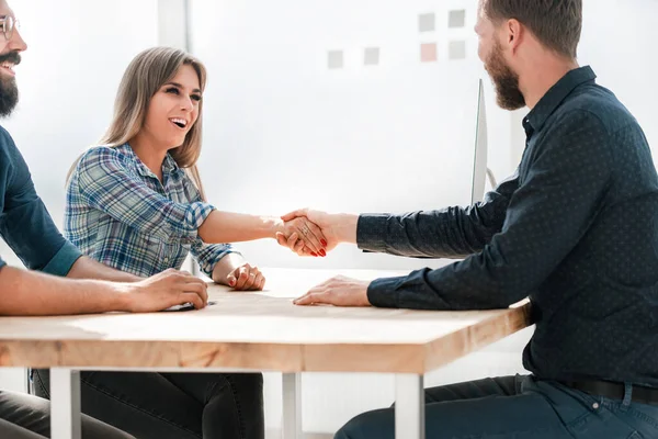 Gülümseyen iş kadını iş ortağıyla tokalaşıyor.