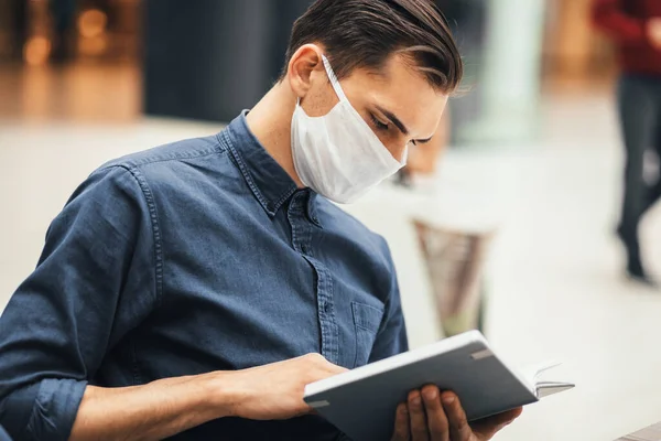 Junger Mann liest ein Buch und sitzt an einem Tisch im Food Court — Stockfoto