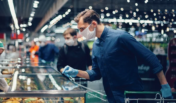 Customer in protective gloves looking at the products in the refrigerator — Stock Photo, Image