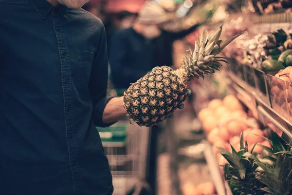 De près. un homme portant un masque de protection cueille un ananas mûr — Photo