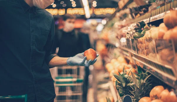 Man in a protective mask when selecting apples at the supermarket. — Stock Photo, Image