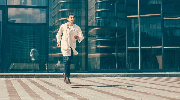 doctor with a stethoscope runs quickly along a city street.