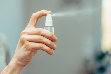Kapat. Ofiste antiseptik sprey kullanan bir çalışan..
