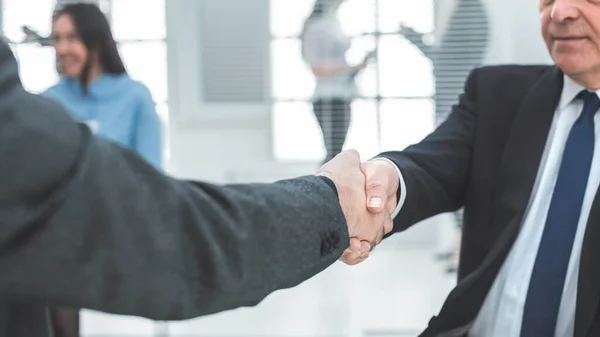 De cerca. apretón de manos de los socios comerciales en el fondo de la oficina . — Foto de Stock