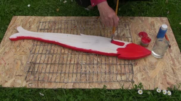 Hombre pintando peces de madera — Vídeo de stock