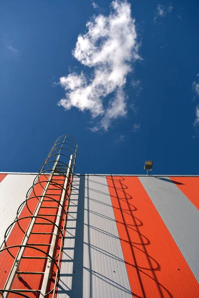 Современная стена здания с металлической лестницей и небом — стоковое фото
