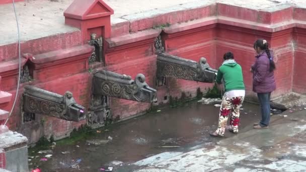 Две девушки пьют воду из фонтана Катманду — стоковое видео