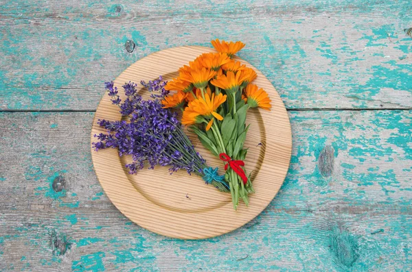 Souci et bouquet de lavande dans une assiette en bois sur la table — Photo
