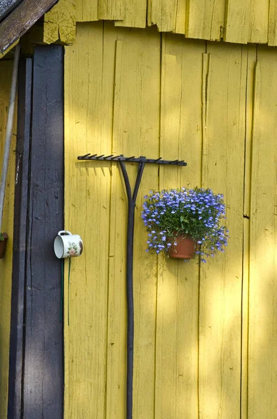 Κίτρινο παλιό αχυρώνα τοίχο με τσουγκράνα και λουλούδι βάζο — Φωτογραφία Αρχείου