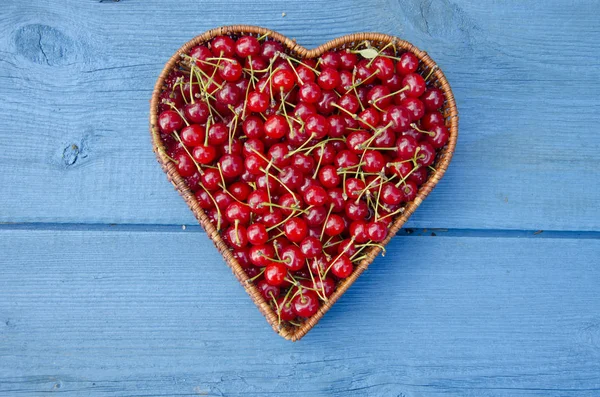 Corazón forma canasta de mimbre de madera llena de frutos de cereza — Foto de Stock