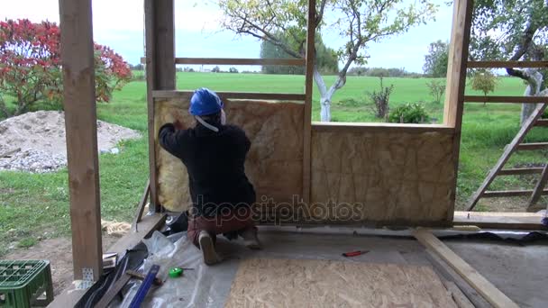 Trabalhador isolante com lã de rocha nova construção de parede de madeira — Vídeo de Stock