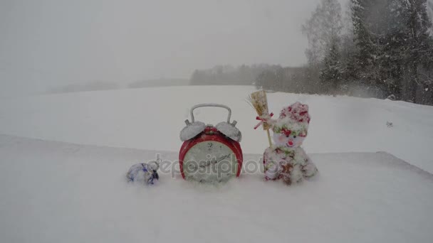 Snowdrift tormenta de nieve, reloj, santa claus y bauble de Navidad en la vieja mesa nevada en el patio de la granja, lapso de tiempo 4K — Vídeo de stock
