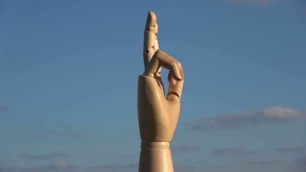 Wooden artist manikin hand rotating on sky background, 4K — Stock Video