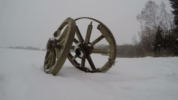 Historical horse carriage wheels on farmland field and winter snowfall, time lapse 4K — Stock Video