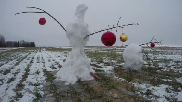Muñeco de nieve en el campo de fin de invierno con bolas de Navidad, lapso de tiempo 4K — Vídeo de stock
