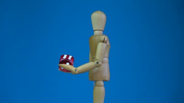 Dřevěná umělec figurína drží červené štěstí kostky a otáčení na modrém pozadí — Stock video