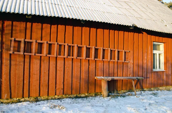 Rote ländliche Holzhauswand im Winter mit Leiter — Stockfoto