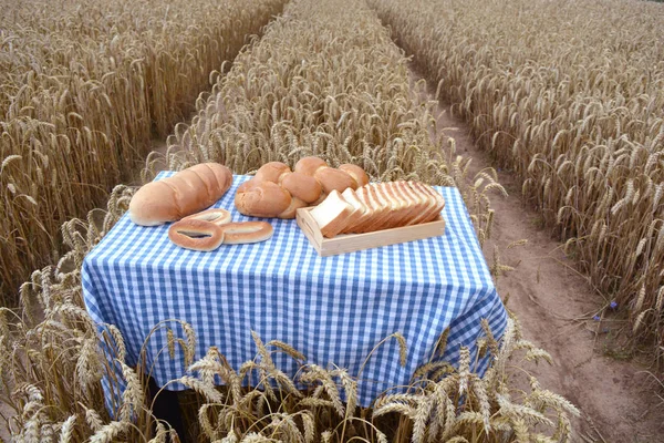 White bread on table in ripe wheat field — Stock Photo, Image