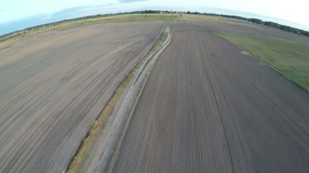 Les drones survolent les champs agricoles d'automne semés et la mauvaise route rurale 